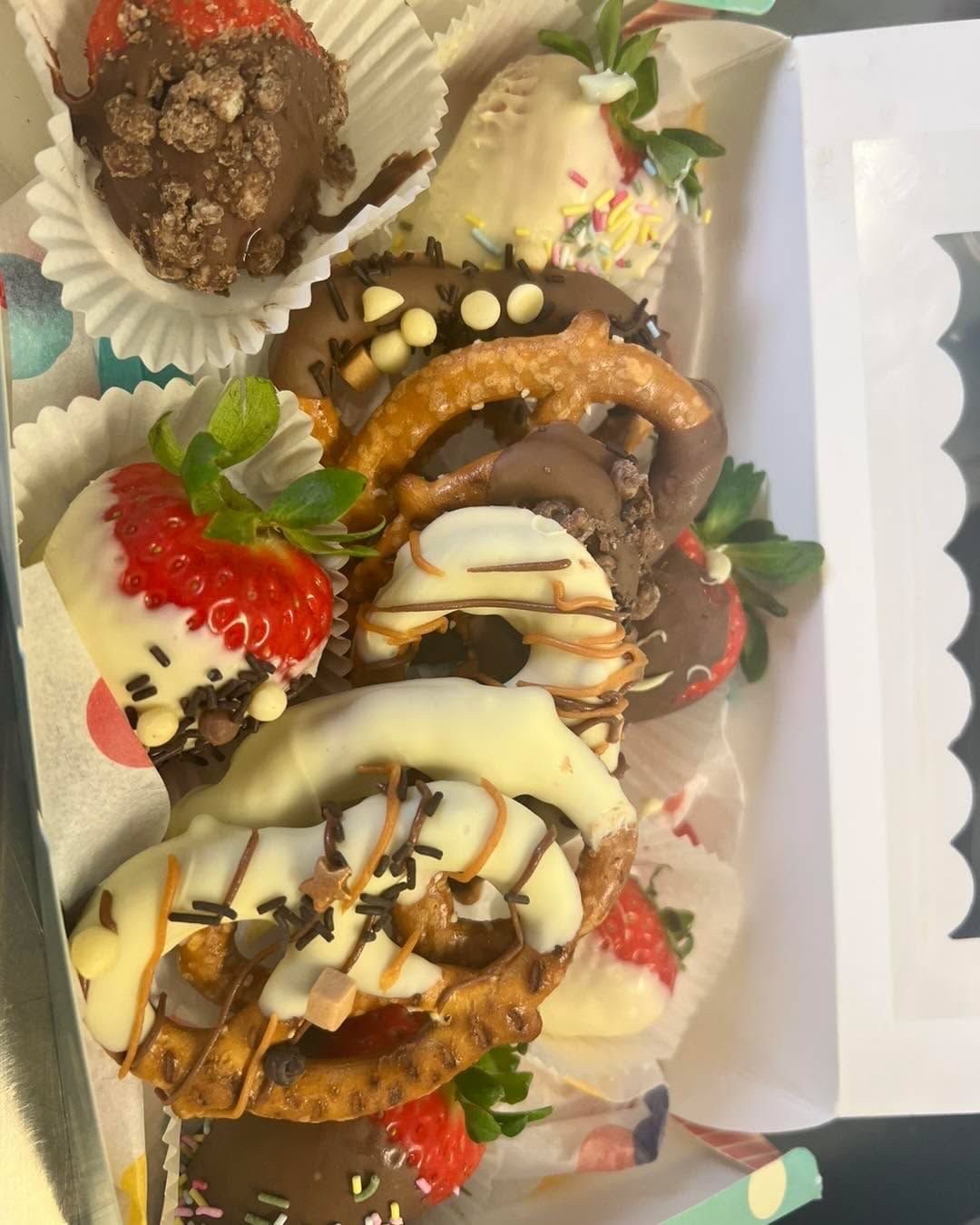 A box of mixed chocolate covered strawberries and pretzels